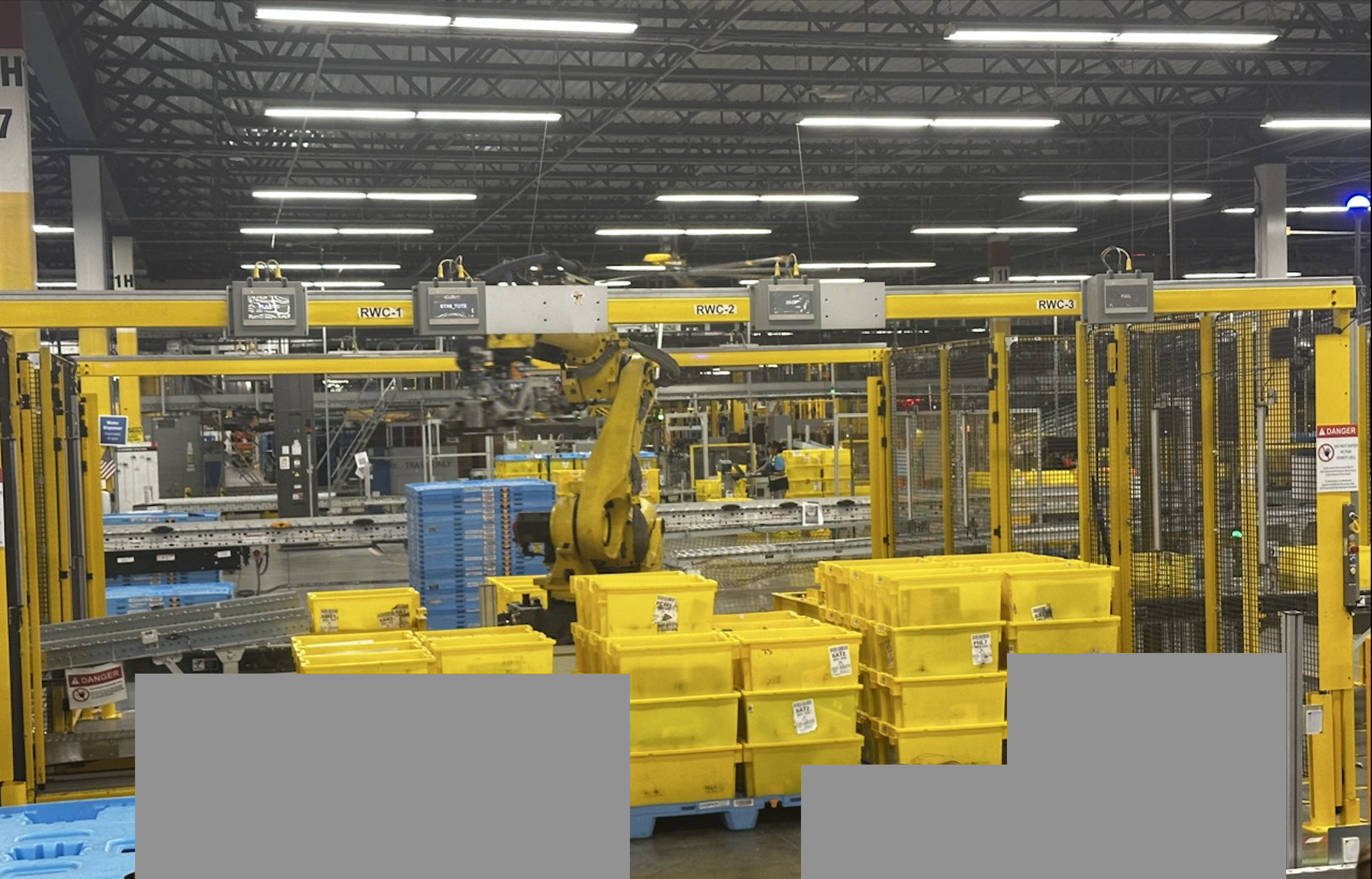 A large robot arm stacking blue totes onto a pallet